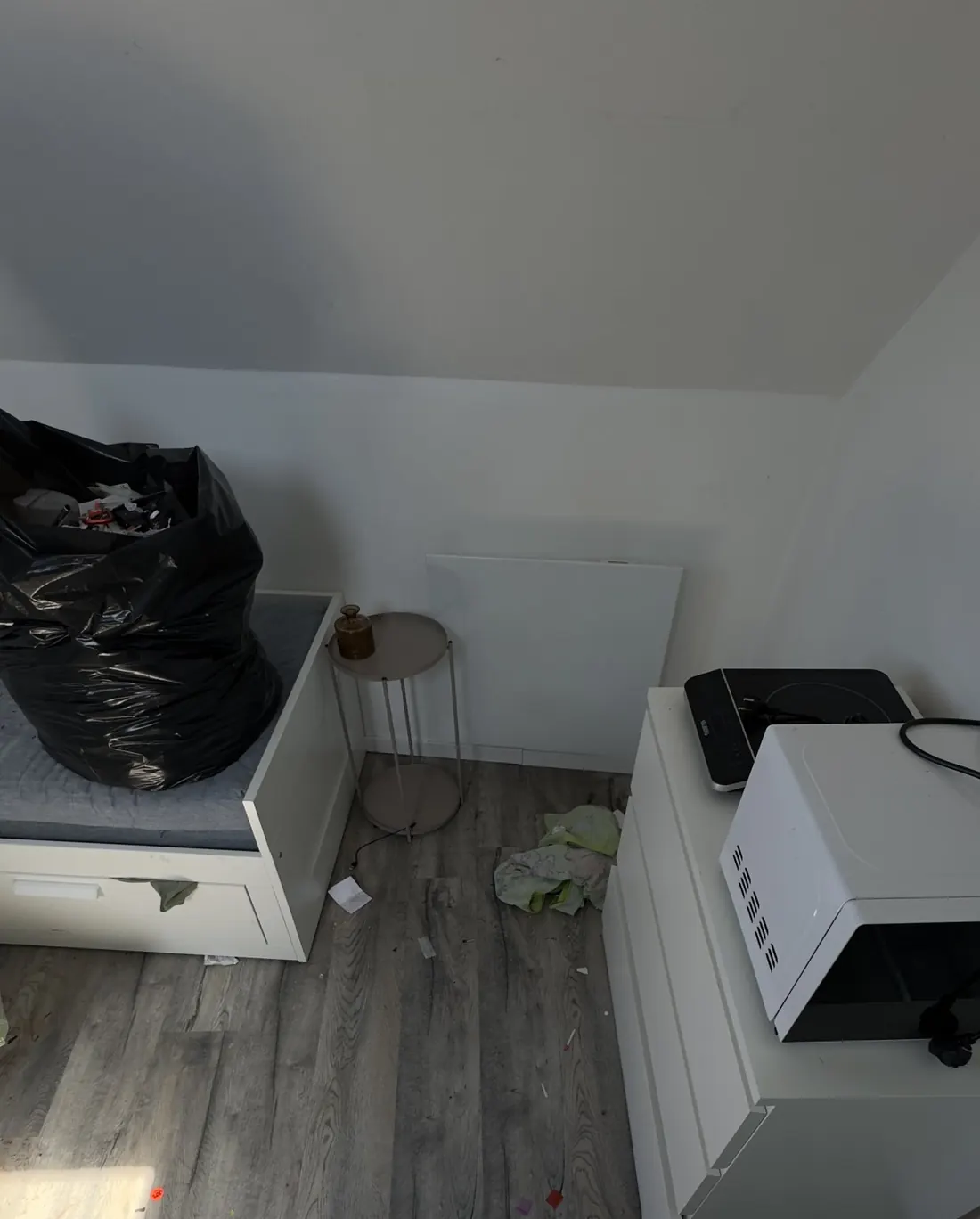 Studio avant le ménage : sac poubelle sur le lit, déchets et taches au sol